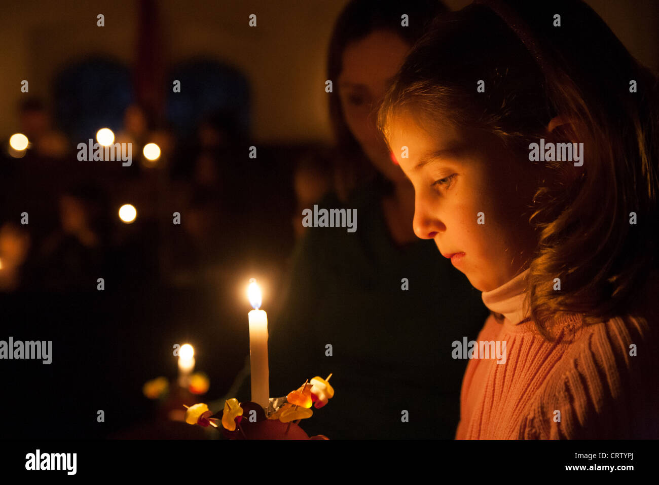 Child Holding Christingle Candle in church service at Christmas Stock Photo