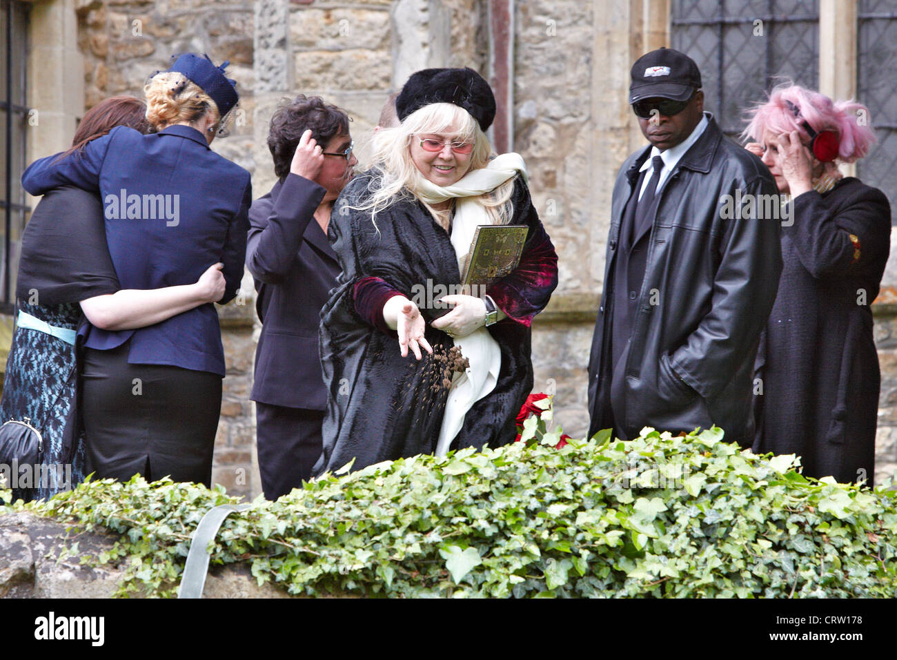 Dwina Gibb (centre), wife of Robin Gibb, throws dirt onto the coffin at the funeral from the Bee Gee singer. Stock Photo