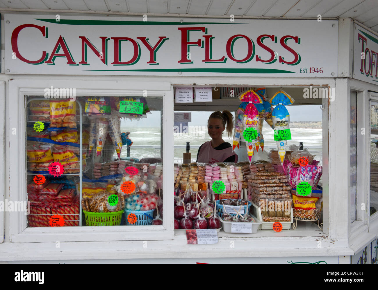 Sweet shop called 'Candy Floss' on Brighton Pier with sweets on display and silhouette of young girl shop assistant Stock Photo