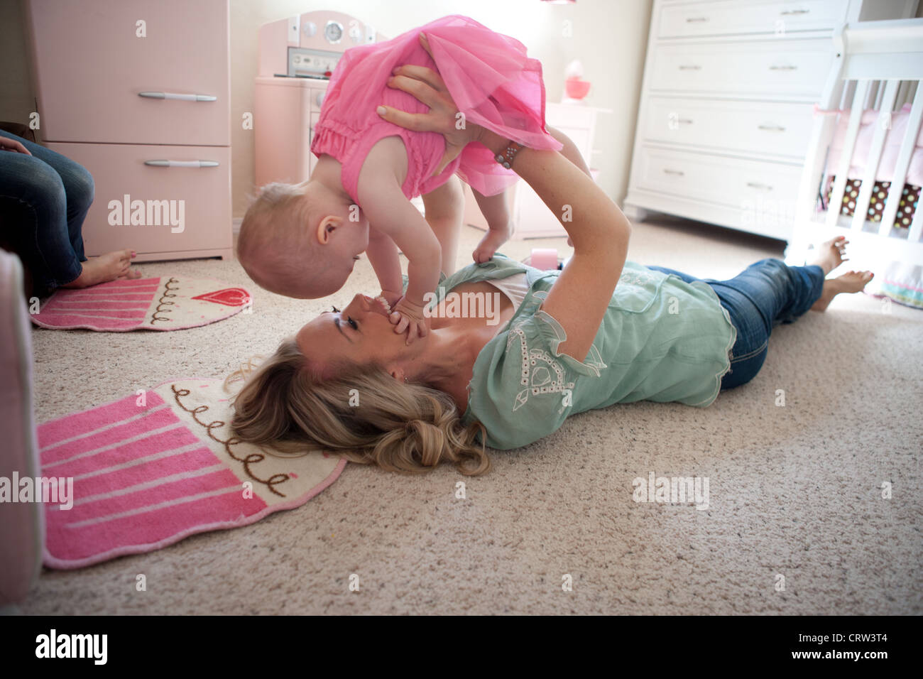 Mom holding her eleven month old girl up and playing in bedroom. Stock Photo