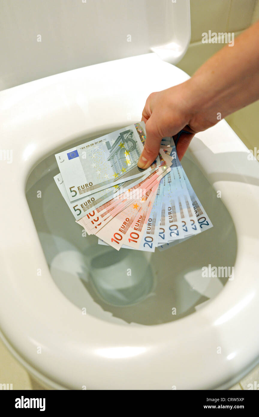 Going down the pan a selection of Euro currency notes in 5s 10s and 20s about to be flushed down a toilet Stock Photo