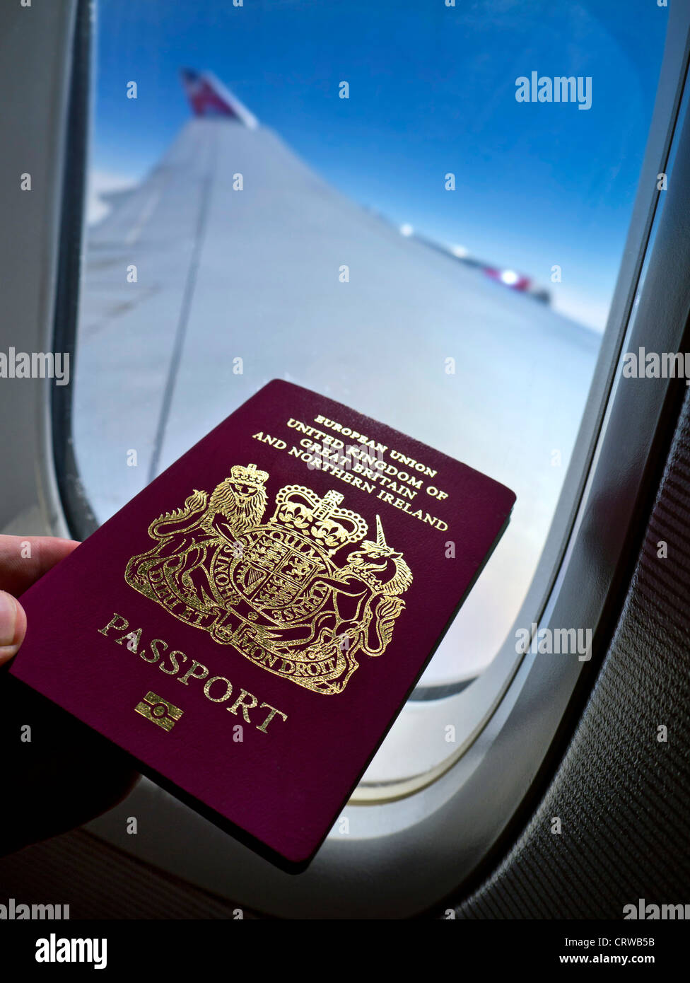 Concept travel image of biometric British passport in Boeing 747 aircraft business class cabin with window wing and sky behind Stock Photo
