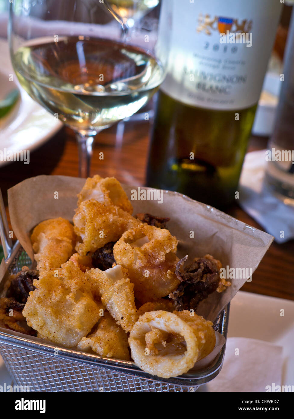 Fried calamari tapas in basket with glass of Bernardus Sauvignon Blanc on table in renowned Rio Grill restaurant Carmel California USA Stock Photo