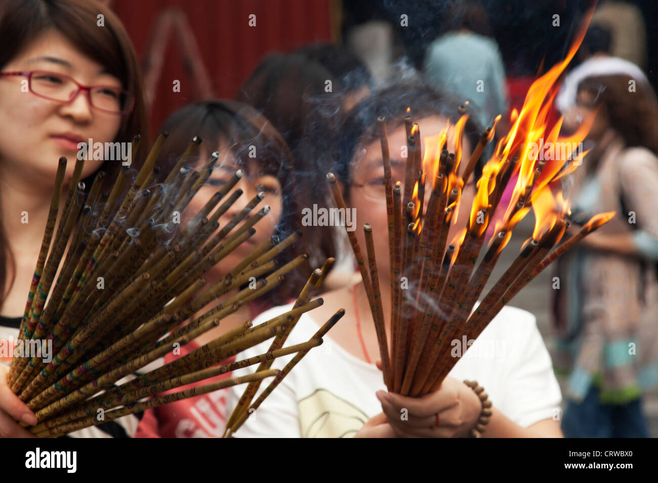 People light incense sticks in a fire at The Yonghe Temple, also known as the "Palace of Peace and Harmony Lama Temple", Beijing Stock Photo