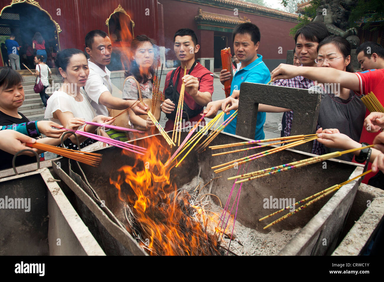 people-light-incense-sticks-in-a-fire-at-the-yonghe-temple-also-known