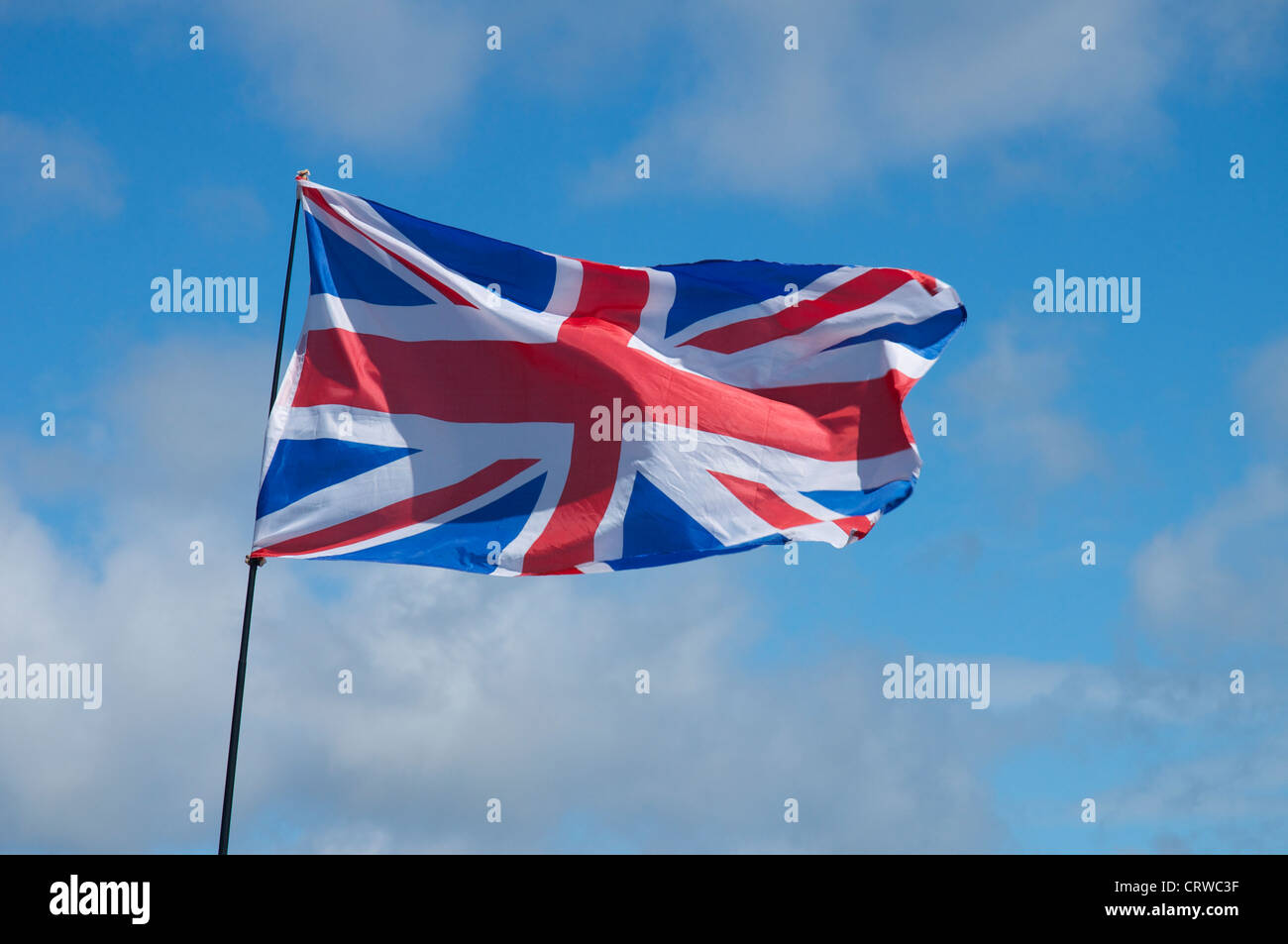Union Jack blowing in the wind against a blue sky Stock Photo - Alamy