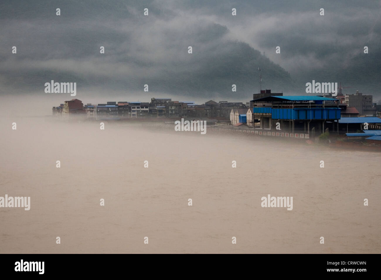A river swells and overflows its banks and floods a town during widespread flooding in Gaungyaun in north Sichuan in China.  Stock Photo