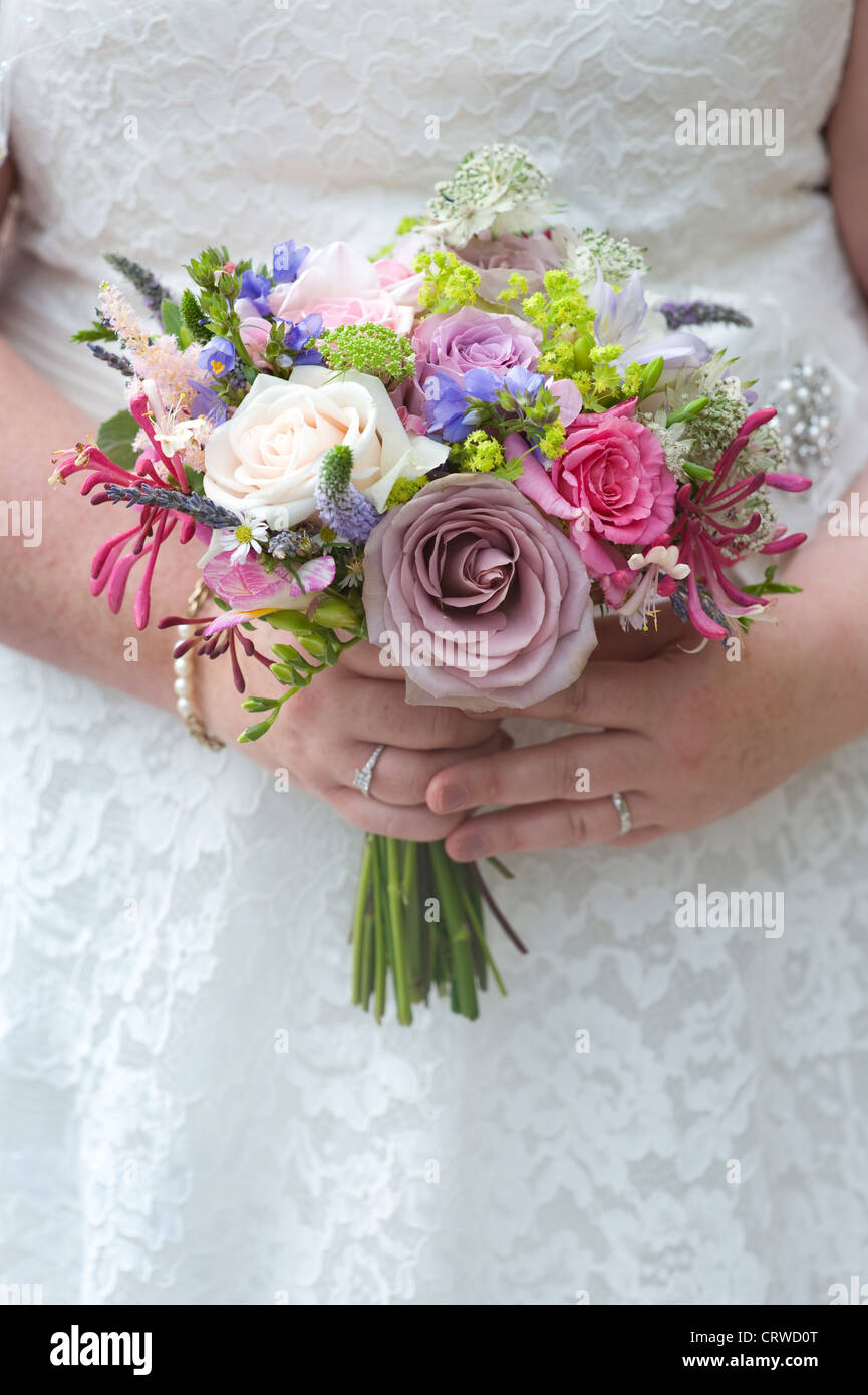 bride holding a wedding bouquet of roses and other flowers Stock Photo