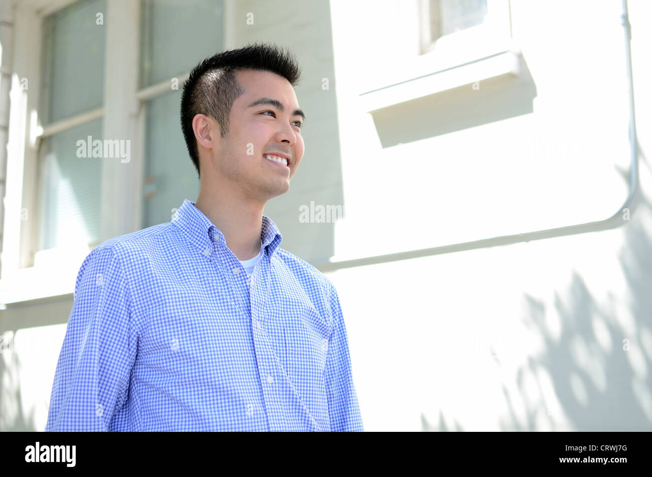Head shot of a young Asian man smiling taken from a low angle Stock Photo