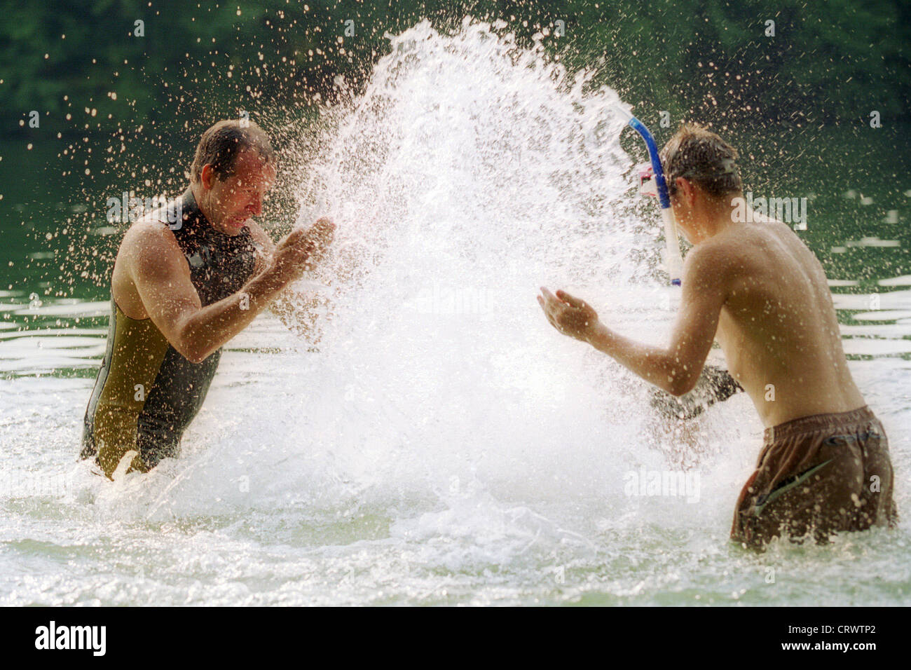 two men spray themselves with water Stock Photo