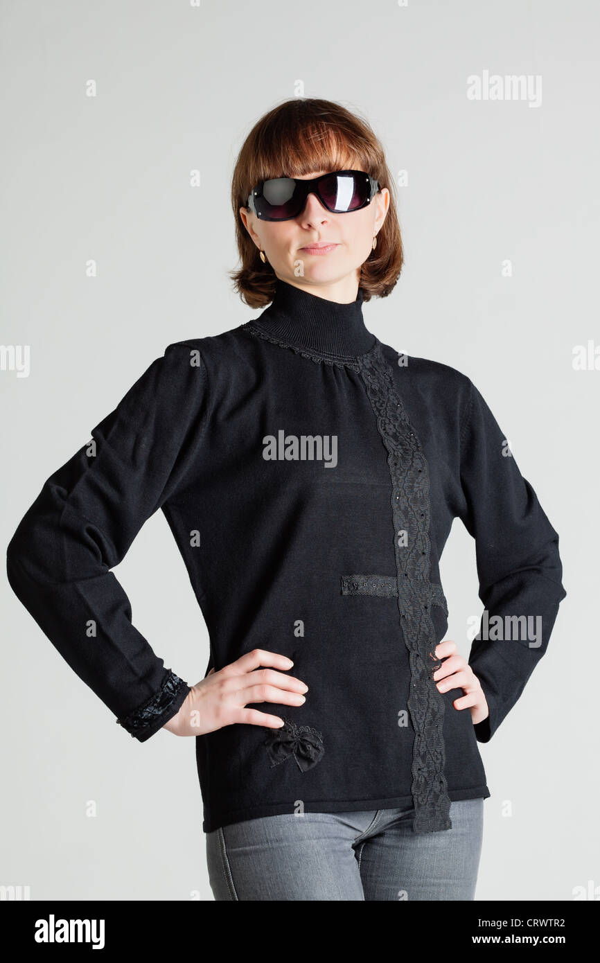 Studio portrait of a middle aged woman in sunglasses standing with arms akimbo Stock Photo