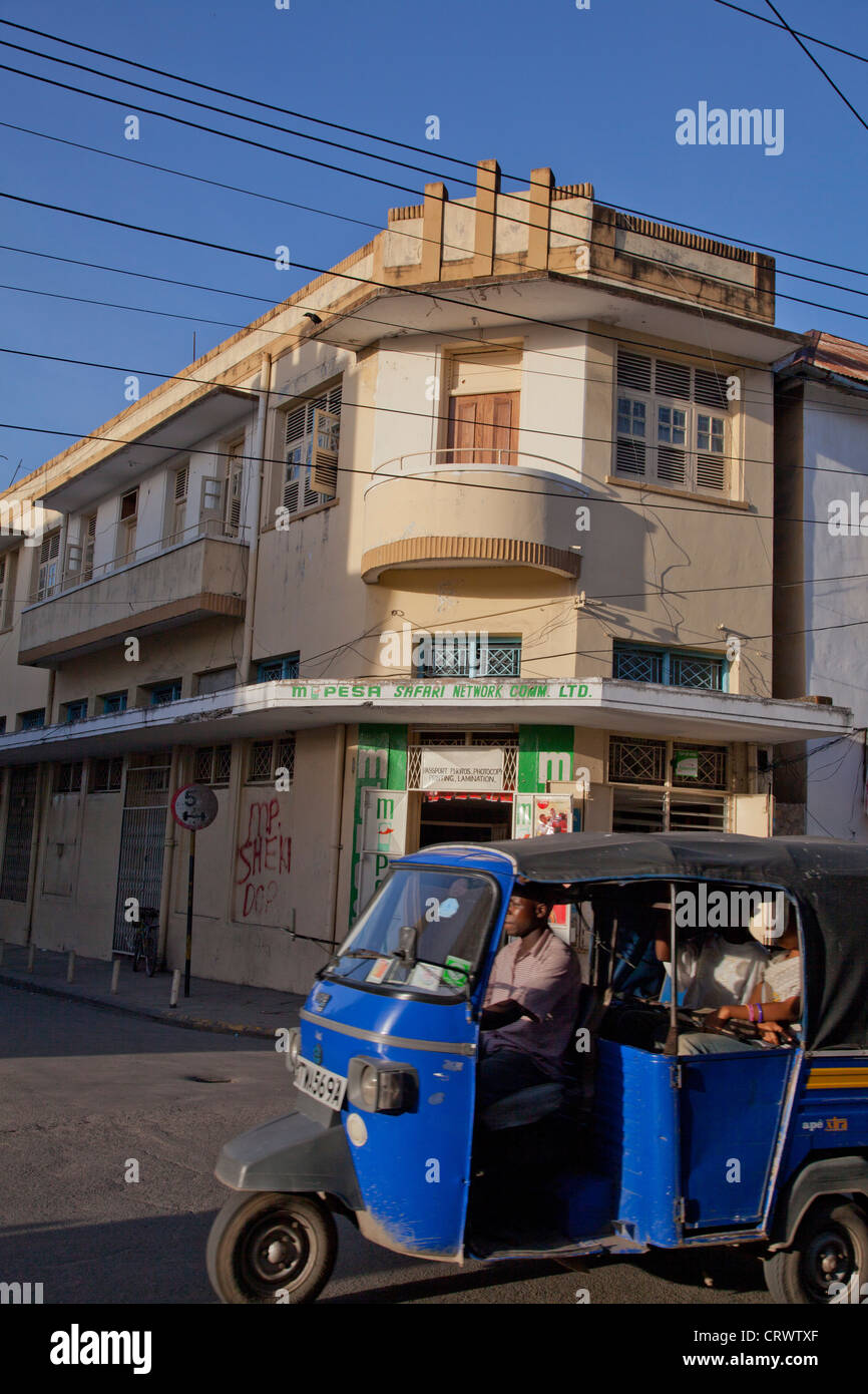Rickshaw taxi drive past colonial buildings in the old town in Mombasa ...