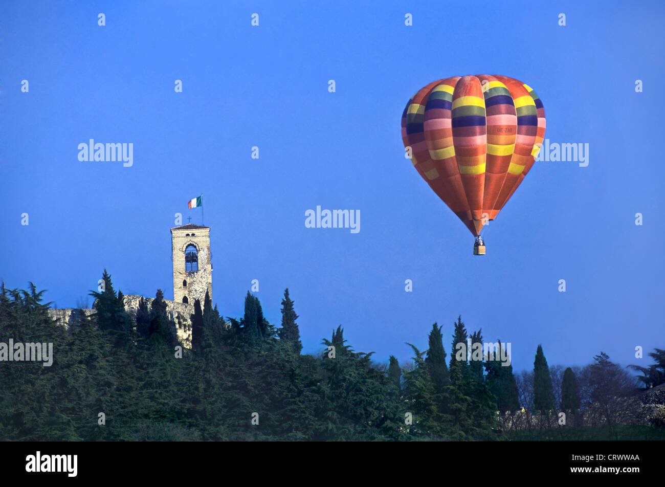 A hot air balloon flies over the bell tower with Italian Flag, Cavriana (Mantova) Lombardy Italy Stock Photo