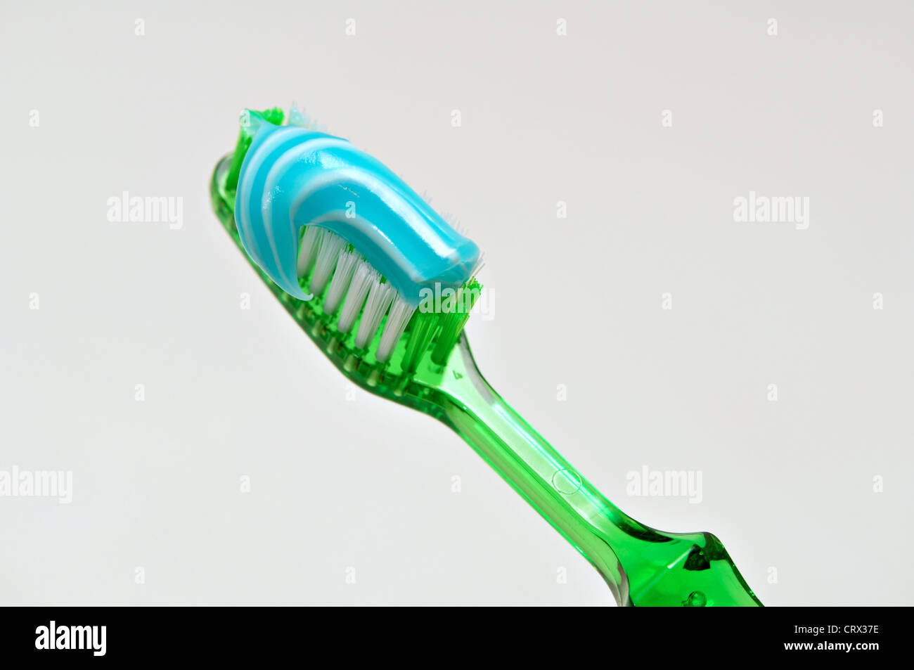 A green tooth brush with blue and white tooth paste on it. Stock Photo