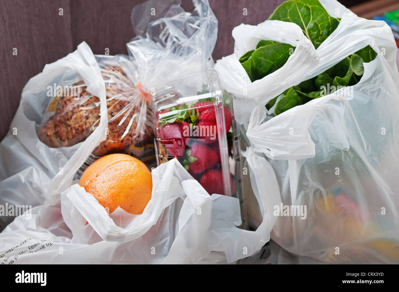 Plastic shopping bags are filled with grocery store purchases. Stock Photo