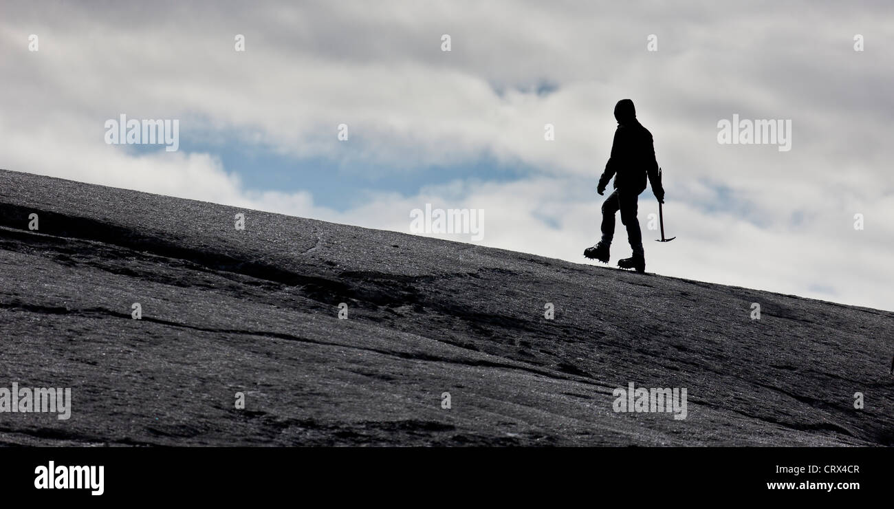 Hiker walking on ash covered glacier,  Svinafellsjokull Glacier, Iceland Stock Photo