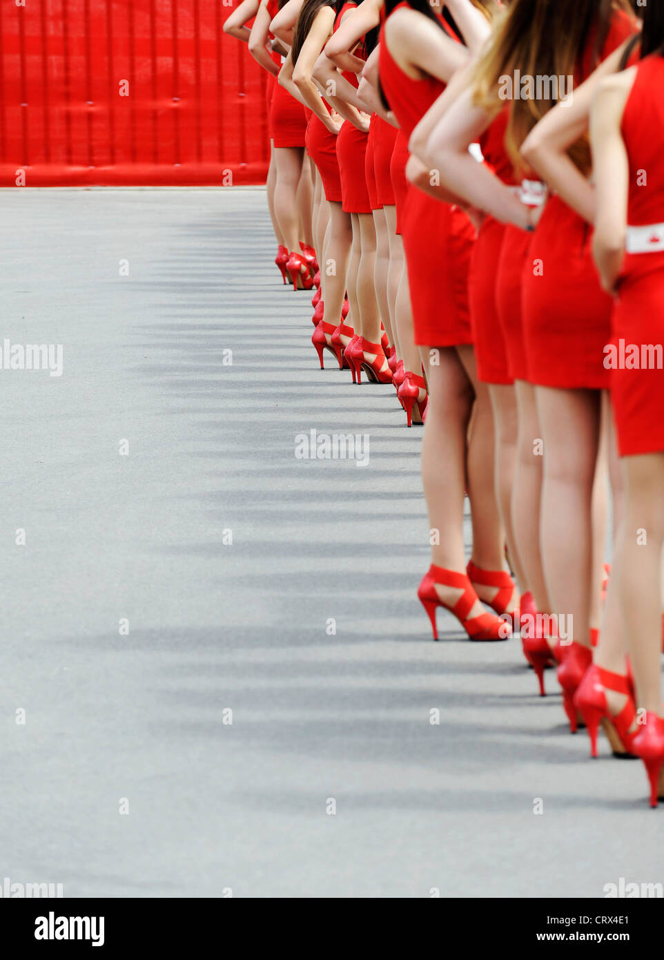women wearing red dresses and red high-heeled shoes stand in a row Stock Photo