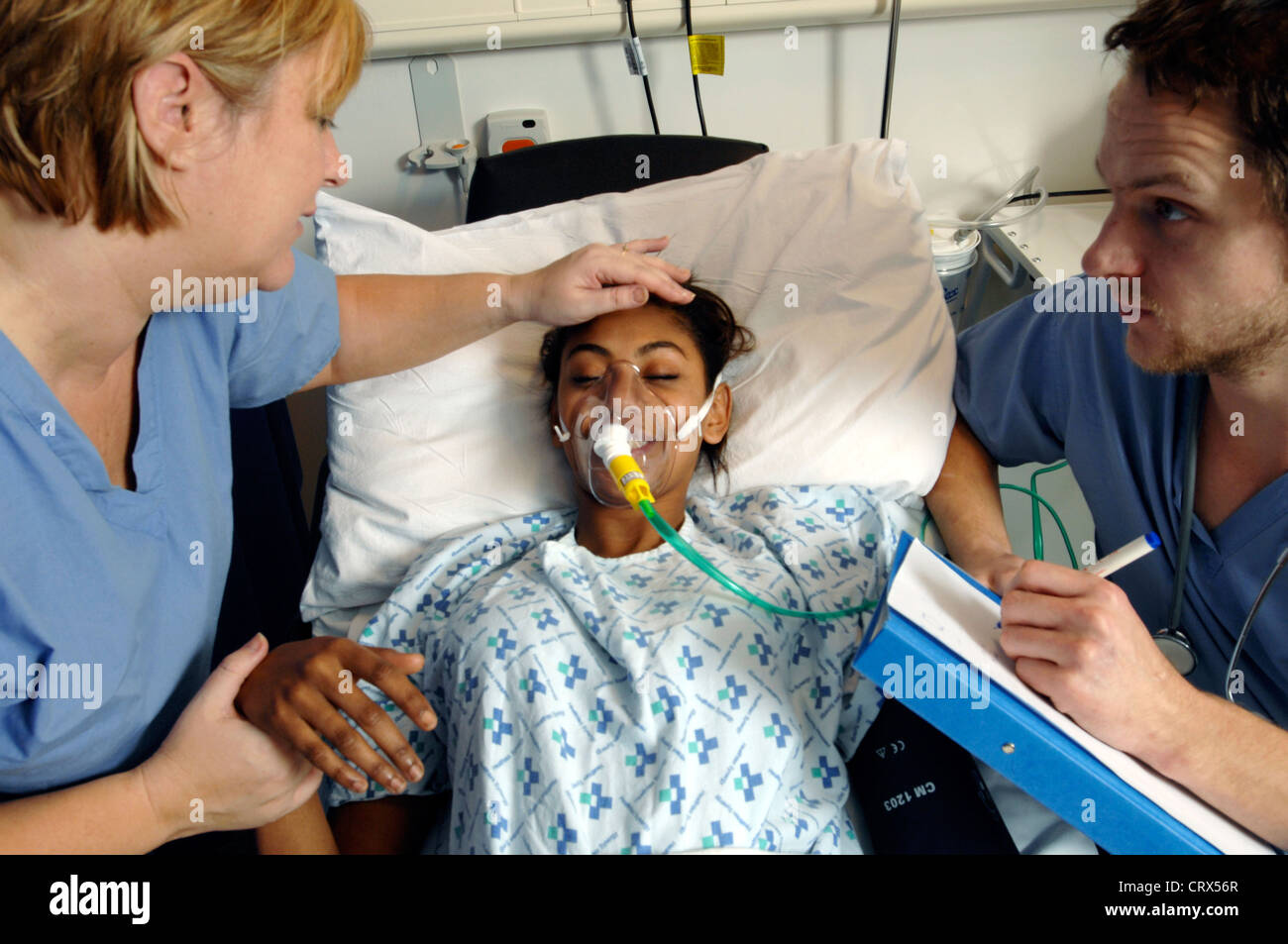 Two nurses at the bedside of a female patient recovering from an