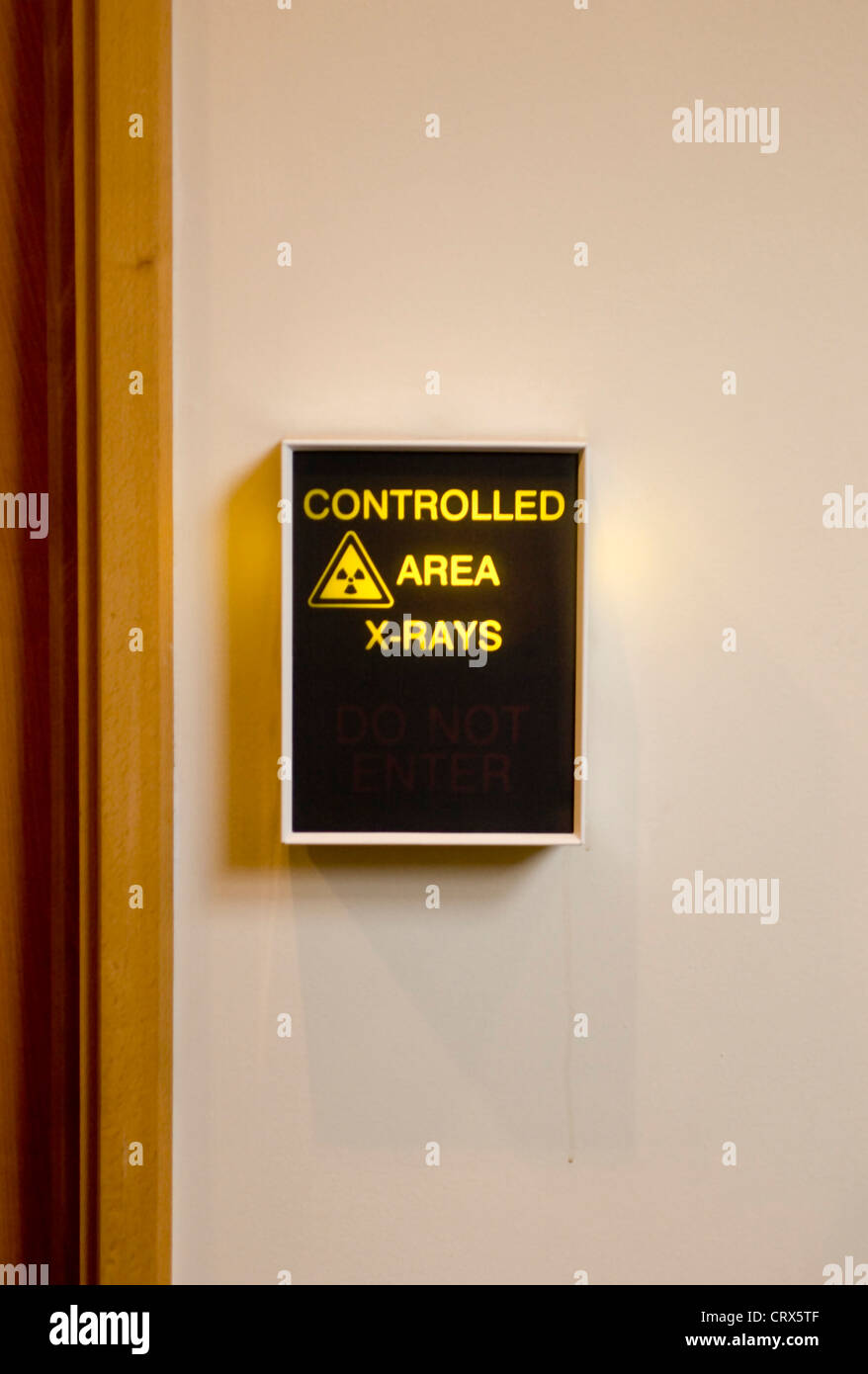An illuminated hospital sign outside a controlled area for x-rays Stock Photo