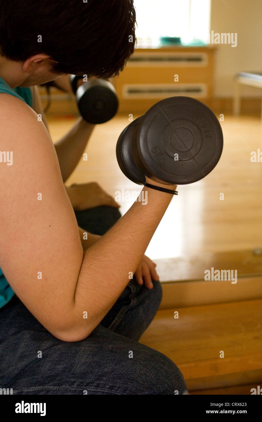 A patient in the physiotherapy department of a London hospital using dumb bells in a series of muscle strengthening exercises. Stock Photo
