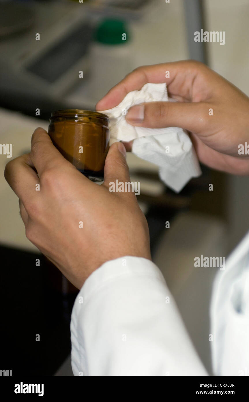 A hospital pharmacist filling a jar with newly prepared skin ointment Stock Photo