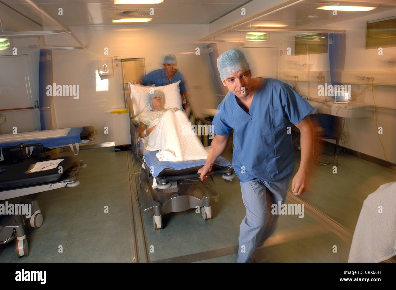 Two hospital porters wheel a patient on a trolley bed to an operating ...