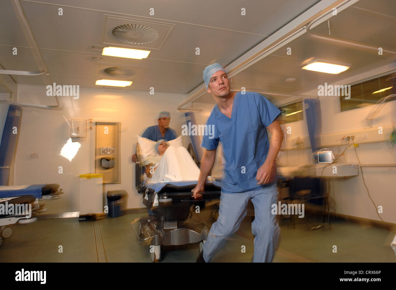 Two hospital porters wheel a patient on a trolley bed to an operating ...