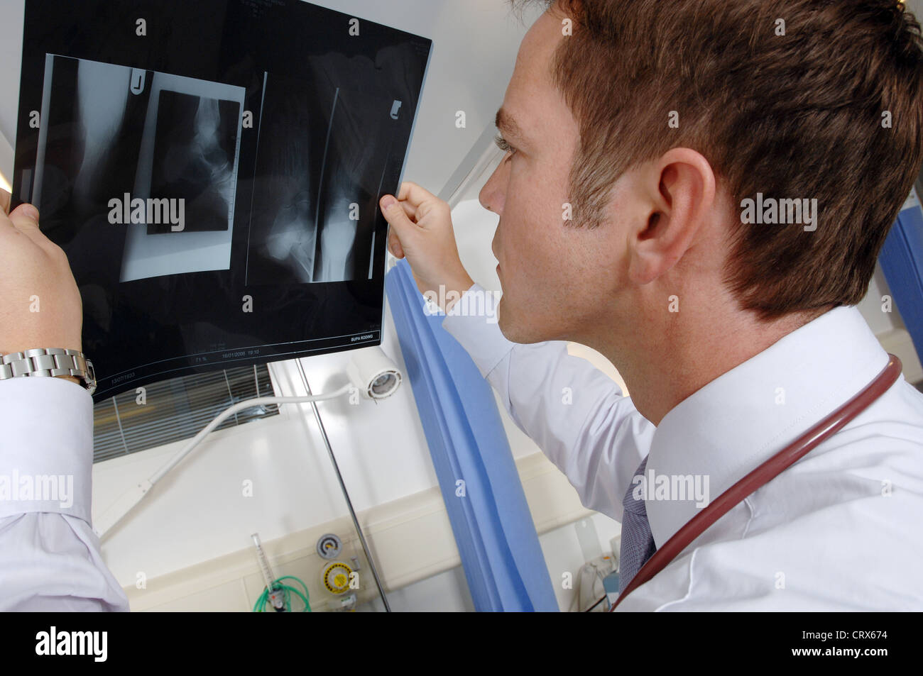 A doctor on his hospital ward round examines a patient's x-ray. Stock Photo