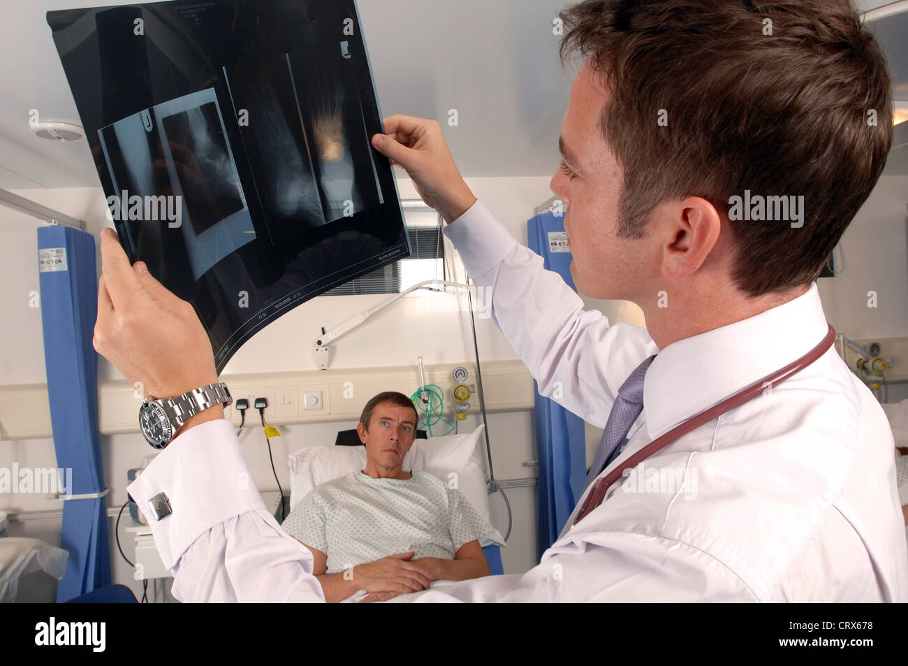 A doctor on his hospital ward round examines a patient's x-ray. Stock Photo