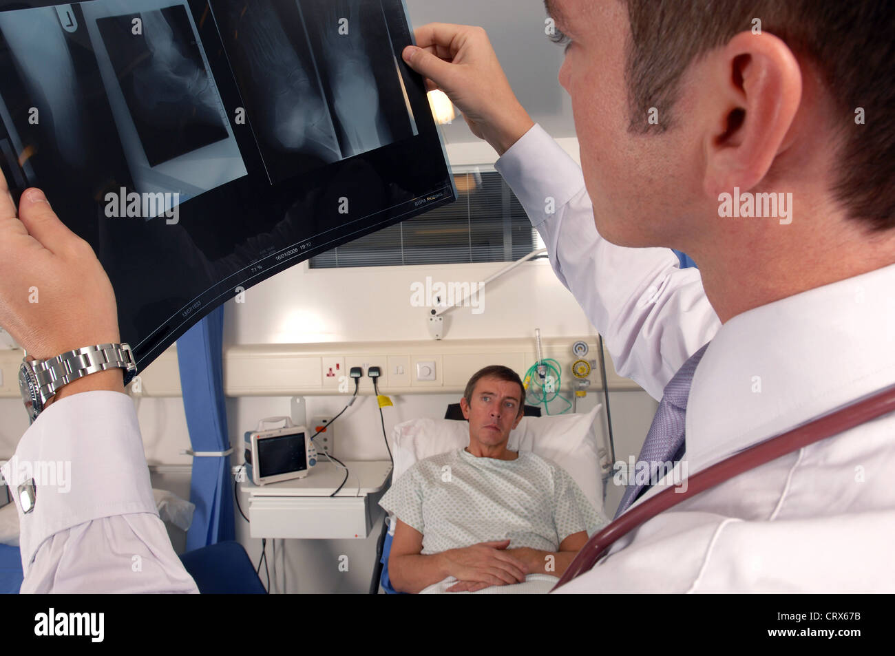 A doctor on his hospital ward round examines a patient's x-ray. Stock Photo