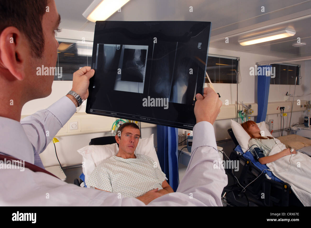 A doctor on his hospital ward round examines a patient's x-ray. Stock Photo