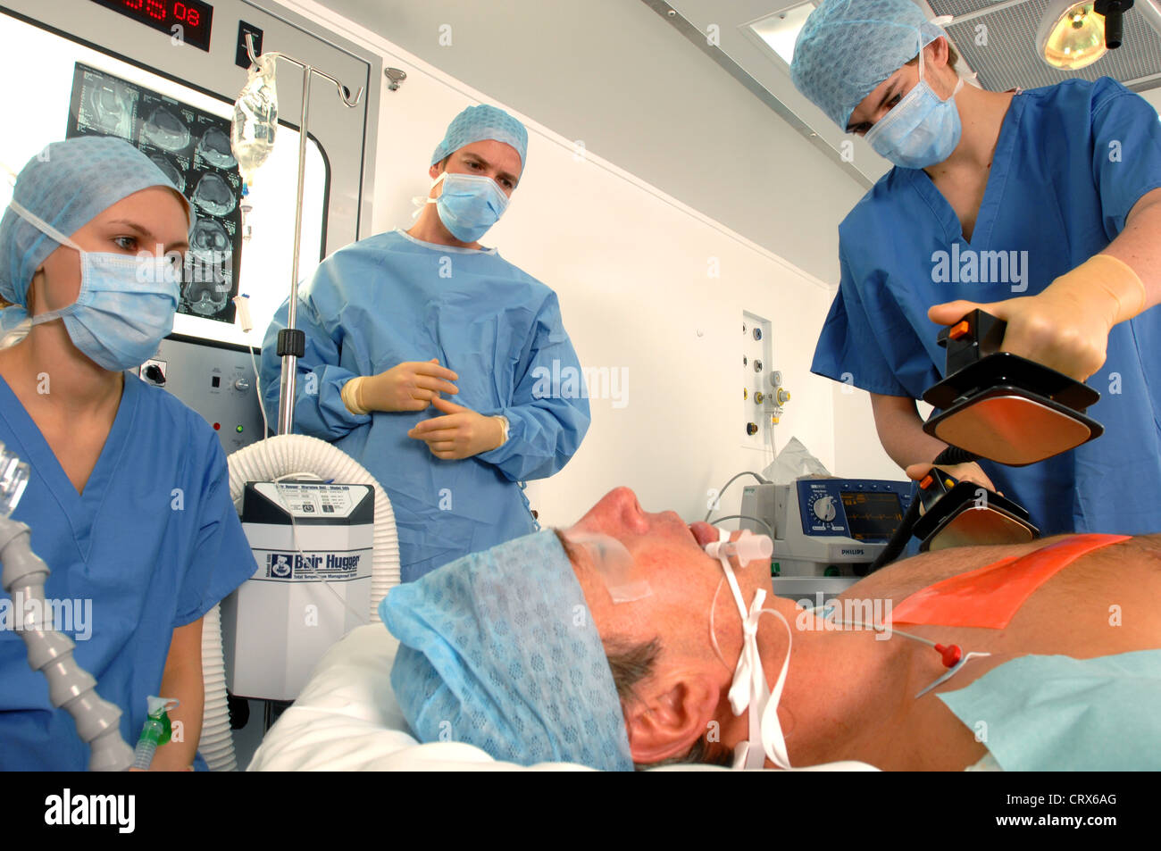 Doctors using a defibrillator to resuscitate a male heart attack victim