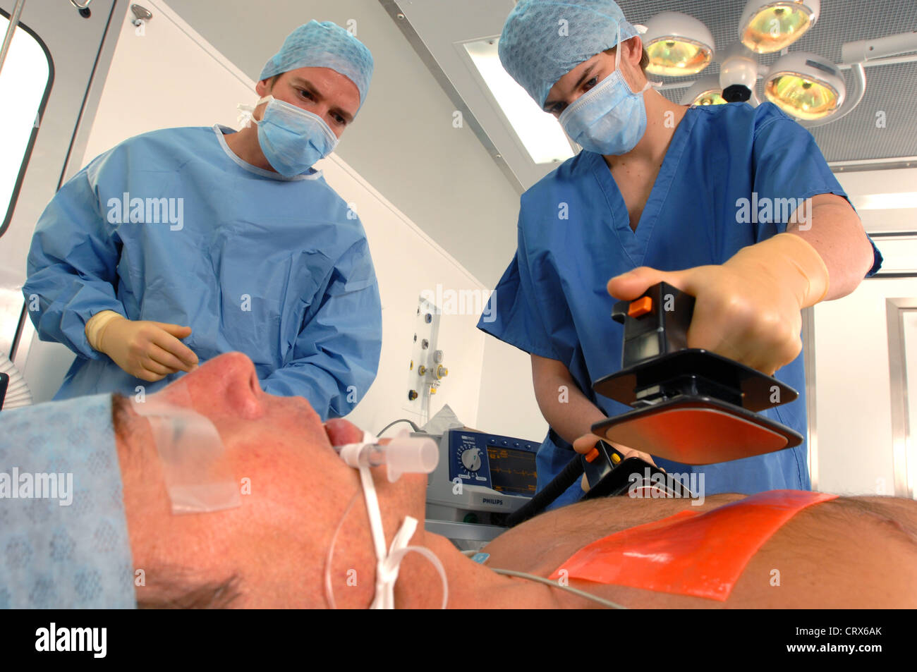 Doctors using a defibrillator to resuscitate a male heart attack victim