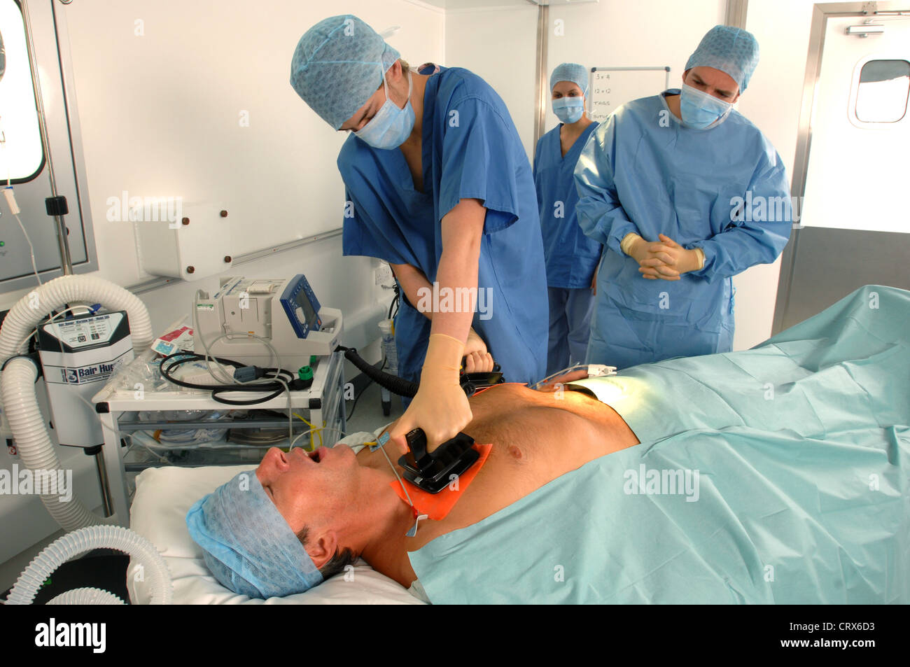Doctors using a defibrillator to resuscitate a male heart attack ...