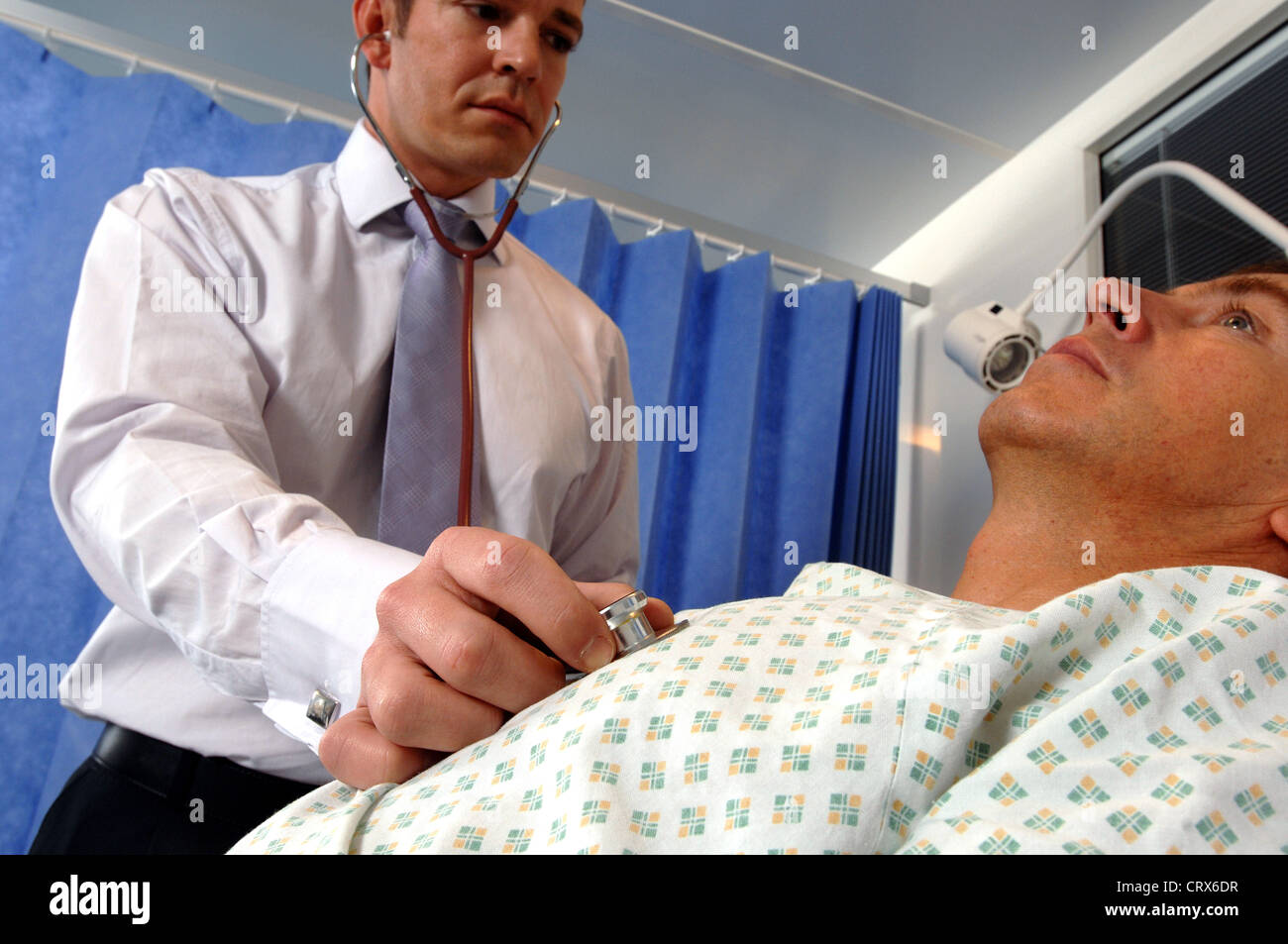 A doctor on his hospital ward round sounds a male patient's chest with ...