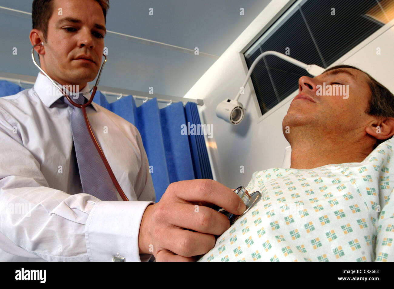 A doctor on his hospital ward round sounds a male patient's chest with ...