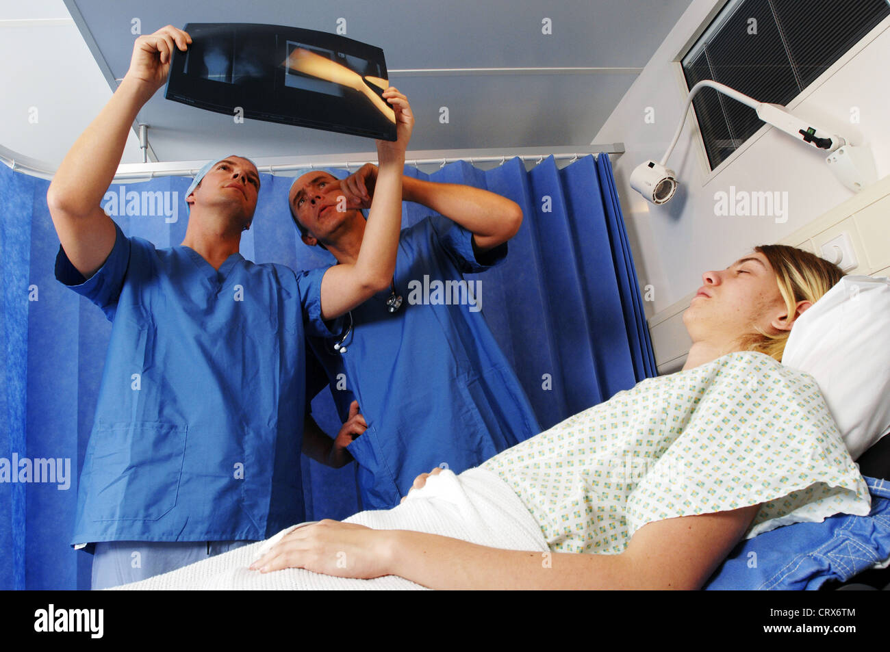 Two surgeons wearing blue surgical caps and gowns, reviewing a patient's x-ray. Stock Photo