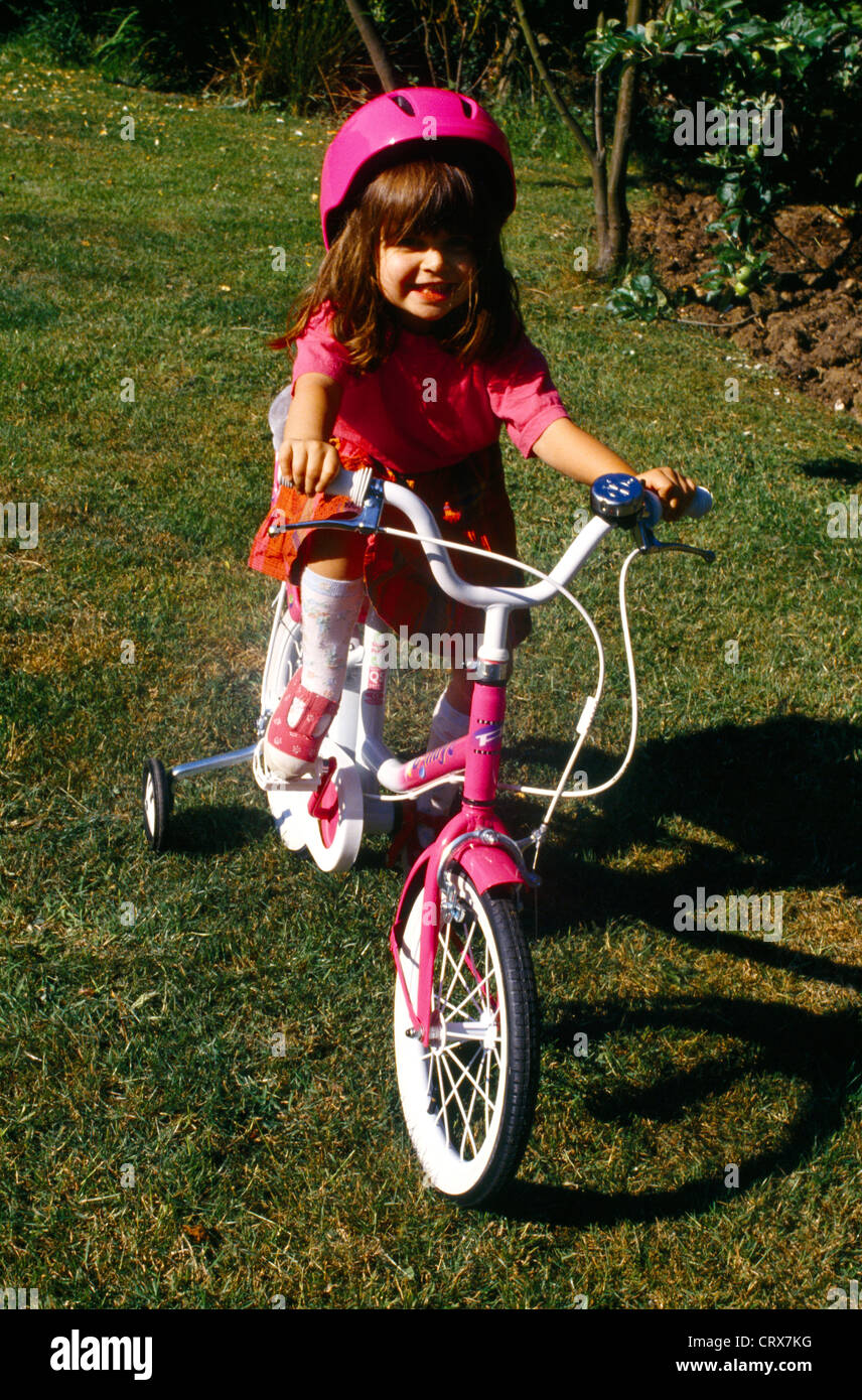 Child Riding Bike With Stabilisers And Cycle Helmet Stock Photo