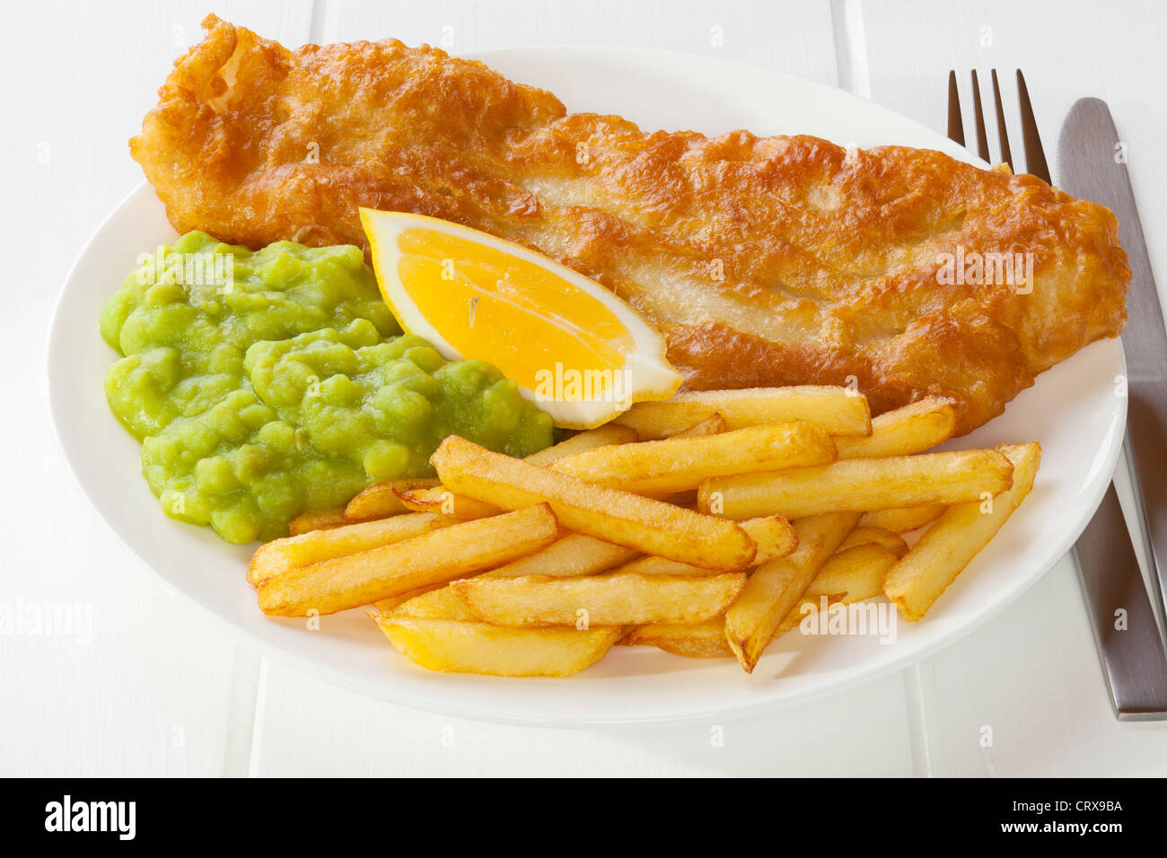 Battered fish served with chips and mushy peas Stock Photo