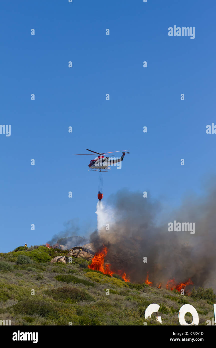 Puerto Duquesa, Costa Del Sol, Spain; A bush fire burns on the hillside. Emergencu helicopters douse the flames Stock Photo