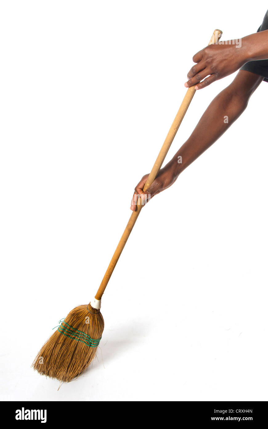 Person sweeping with an African broom which is hand made using dried straw, wood handle, and string, wire and tape. Stock Photo