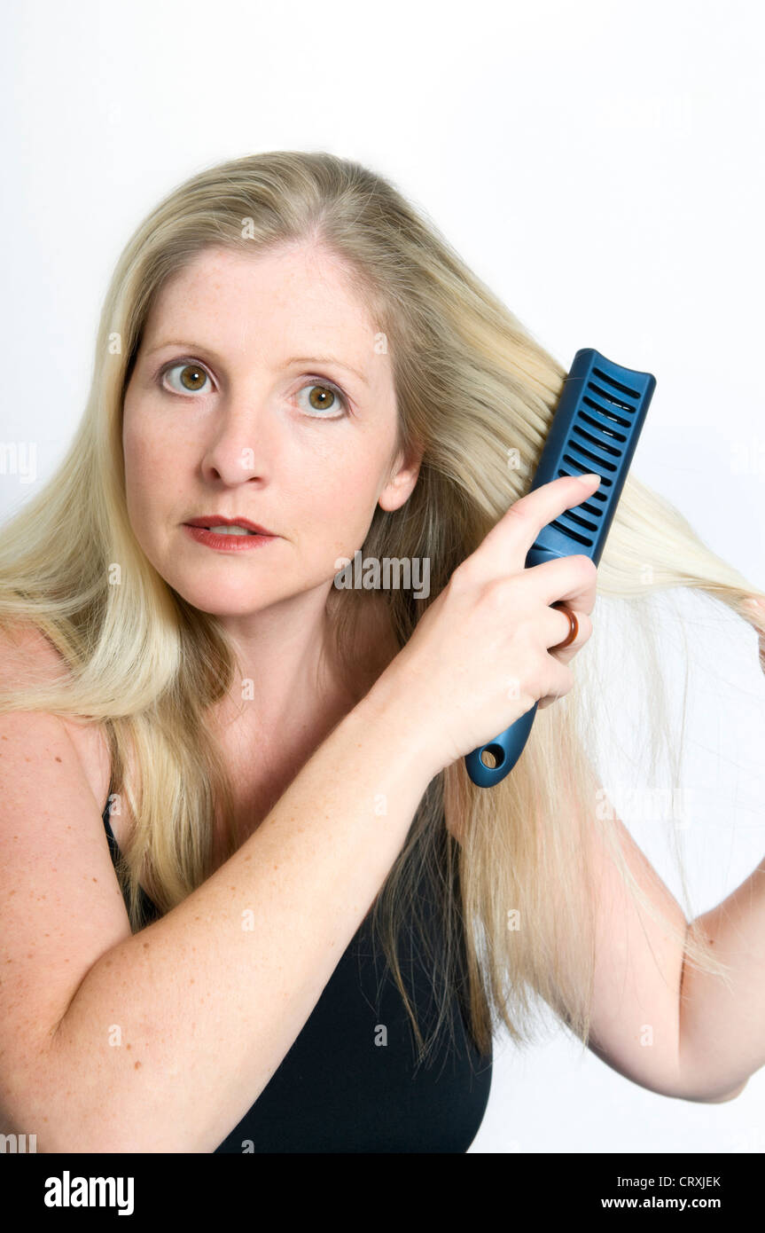 Studio shot of attractive young Caucasian woman brushing hair against a white background Stock Photo