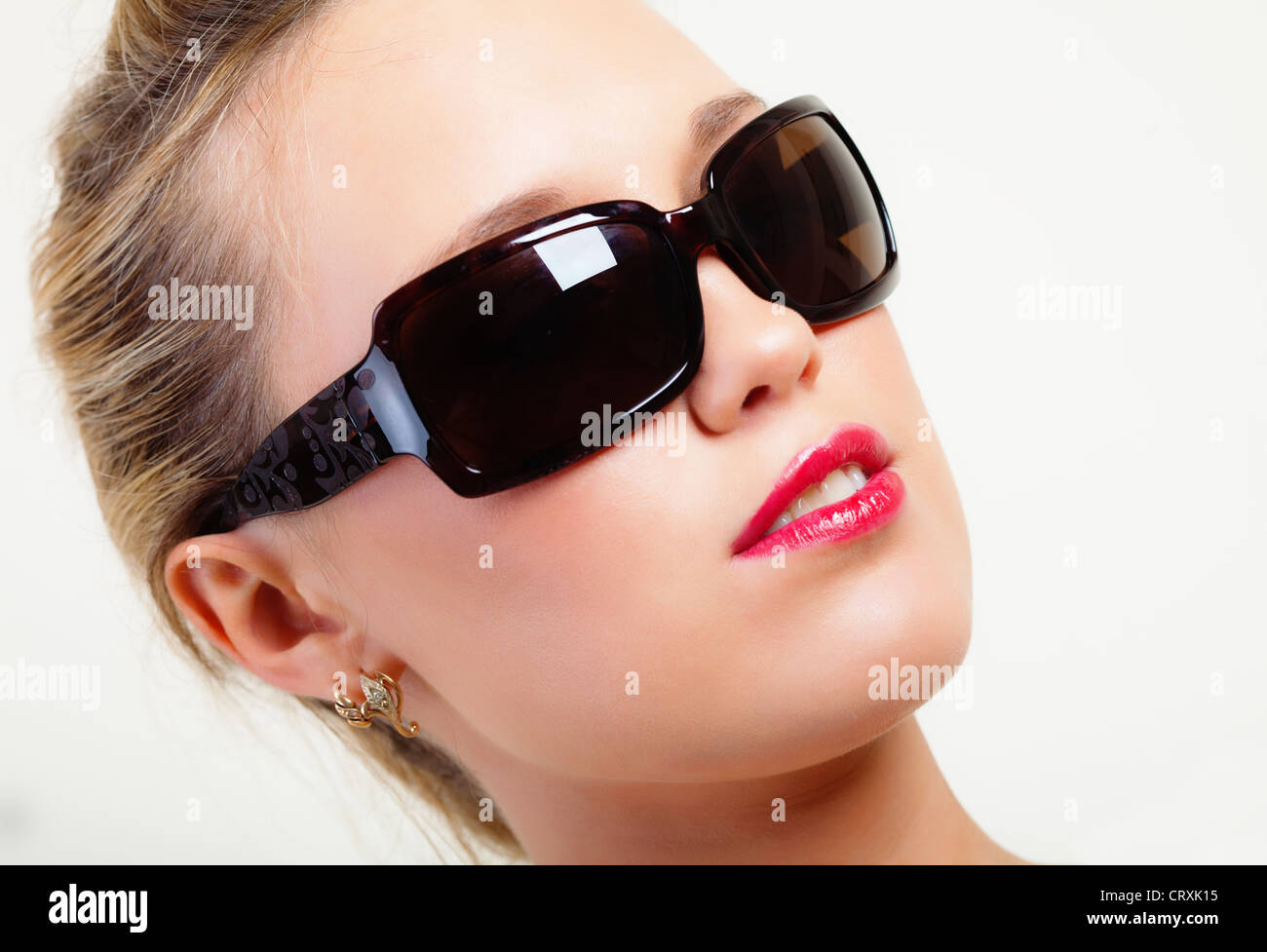 Portrait of brightly lit beautiful young woman in sunglasses Stock Photo