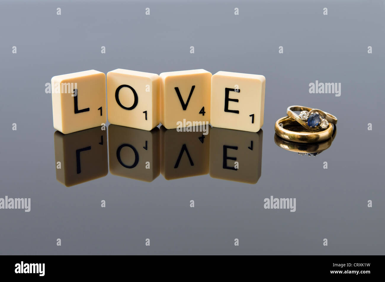 Wedding and engagement ring with scrabble letters spelling out the word love with reflection, concept of love or valentine Stock Photo