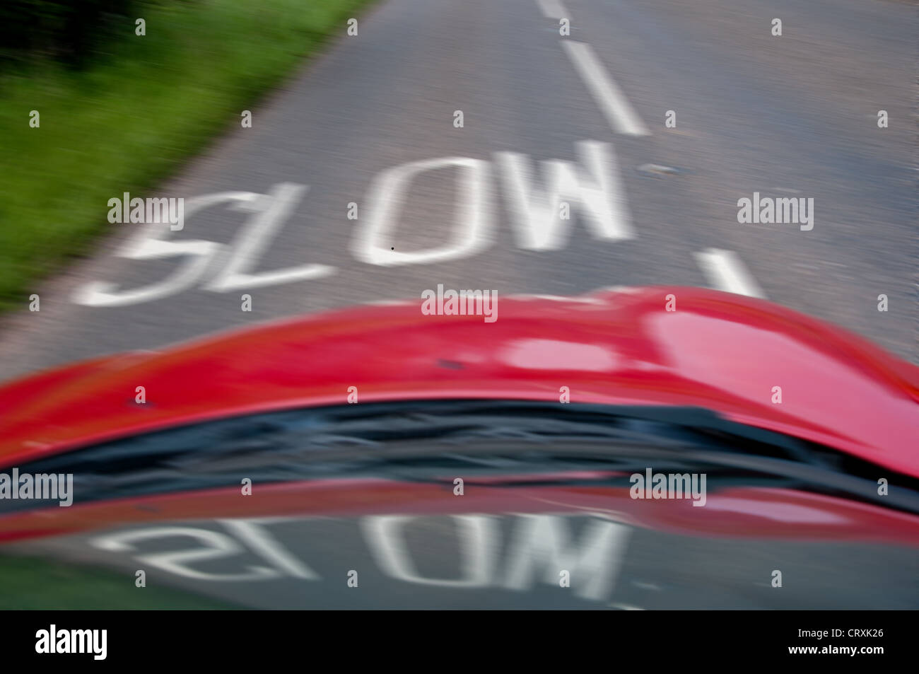 Slow warning sign markings on road photographed from moving car with motion blur. Stock Photo