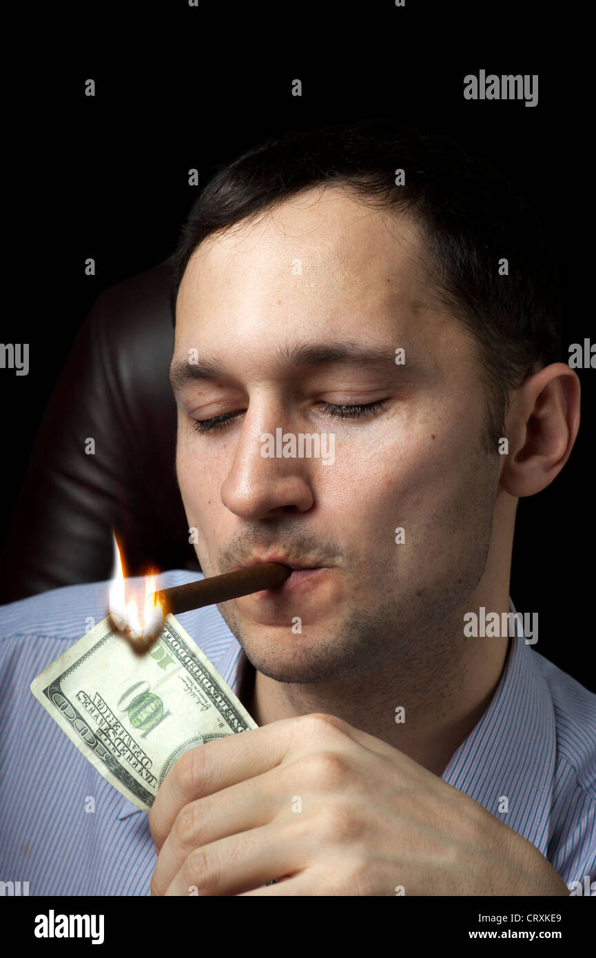 Young handsome man lighting his cigar with 100 note Stock Photo Alamy