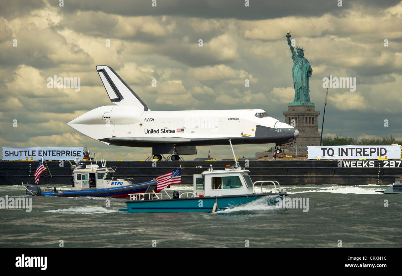 The space shuttle Enterprise atop a barge passes the Statue of Liberty on its way to the Intrepid Sea, Air and Space Museum where it will be permanently displayed June 6, 2012 in New York, NY. Stock Photo