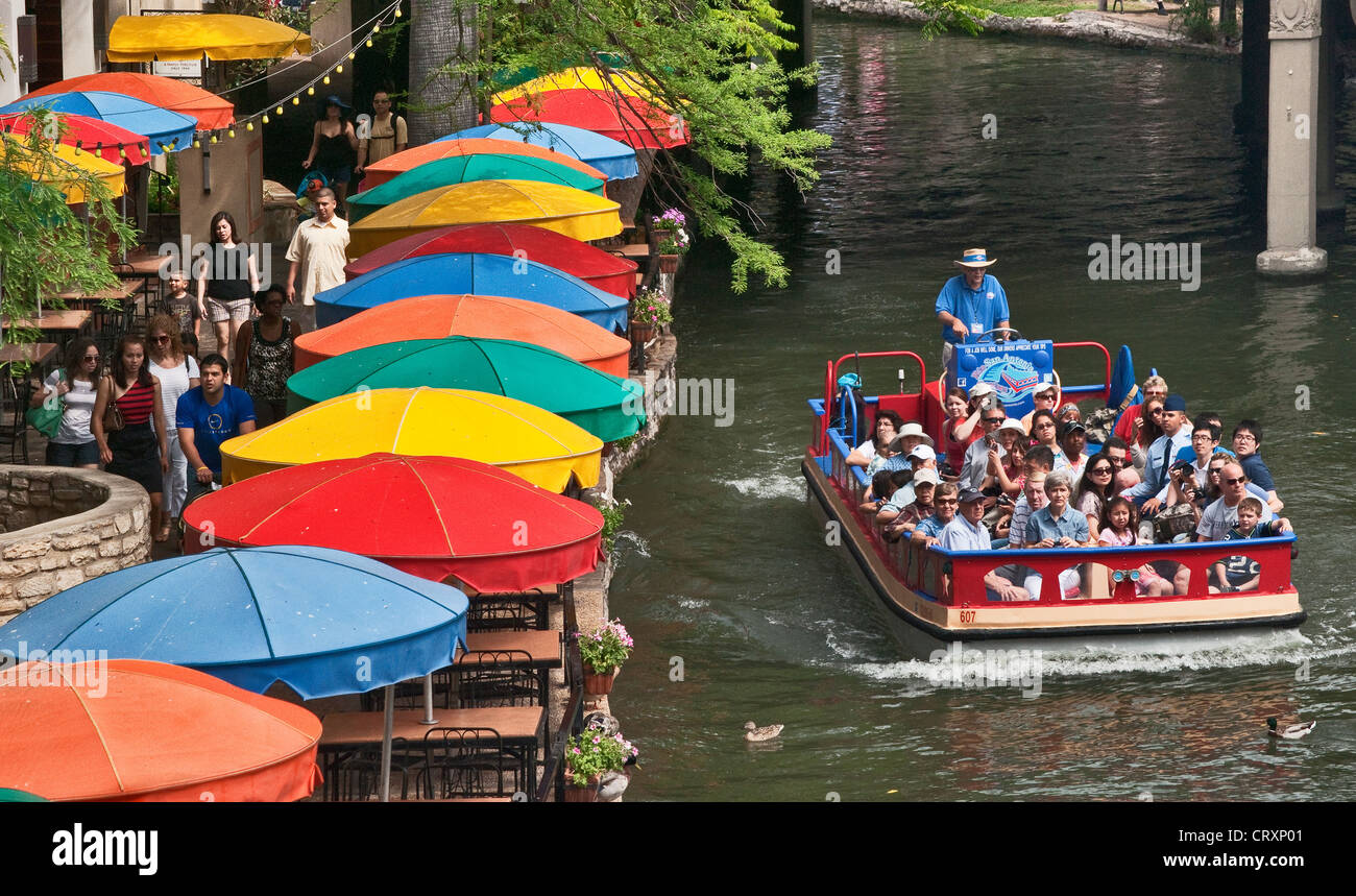 River barge, tourists sightseeing, on River Walk channel, outdoor cafe umbrellas, San Antonio, Texas, USA Stock Photo