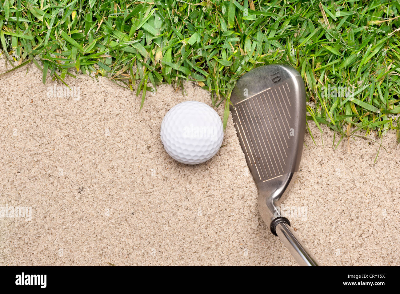 A golf ball in a sand trap getting ready to be hit with an iron. Stock Photo