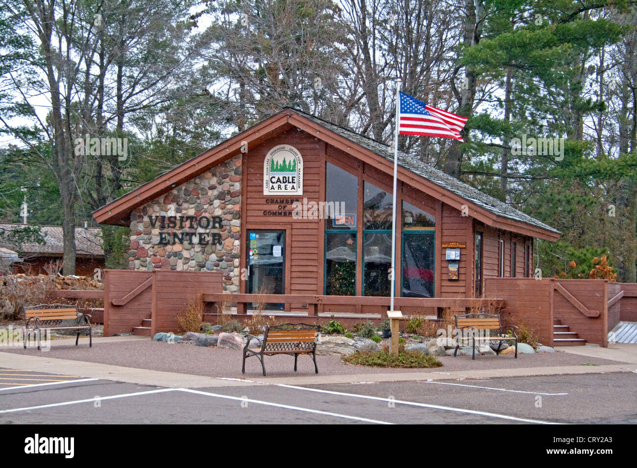Woodsy log cabin style Visitors Center with American Flag waving. Cable